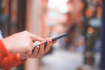 Cropped Hands Of Woman Using Phone On Footpath