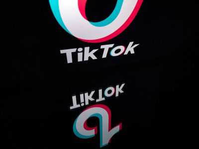 TikTok logo on a black background reflecting on a glass surface