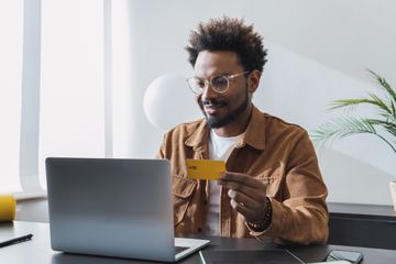 Someone shopping online on a laptop with a credit card in hand. 