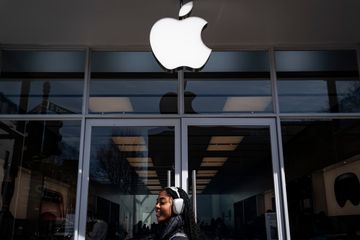 Someone walking in front of an Apple store.