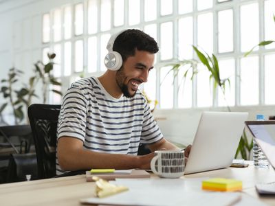 Person wearing headphones and using a computer while smiling