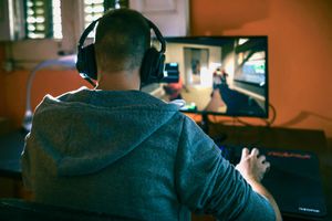 Young man sitting at his mini PC, playing computer games.