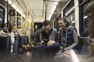 Smiling commuters texting with smartphone on bus