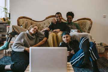 A group of people gathered around a laptop smiling